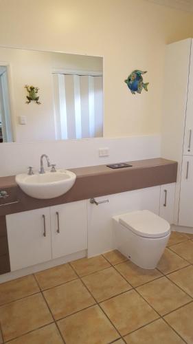 a bathroom with a sink and a toilet and a mirror at Nautilus Holiday Apartments in Port Douglas