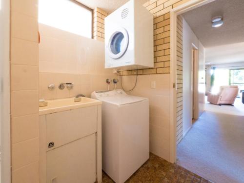 a small bathroom with a sink and a washing machine at Golden Shores Unit 3 21 Landsborough Parade in Caloundra