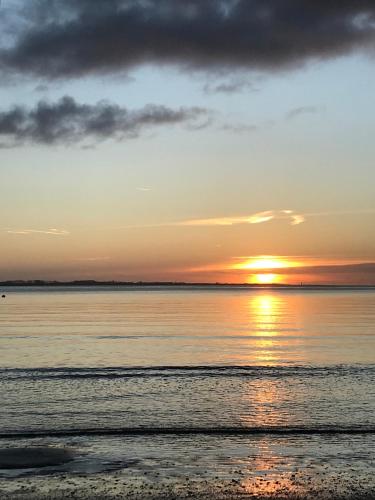a sunset over the water on a beach at Bed & Breakfast Van Marion in Oostvoorne