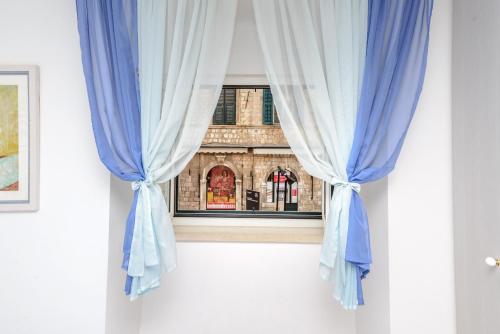 a window with blue curtains in a room at Studio Stradun in Dubrovnik
