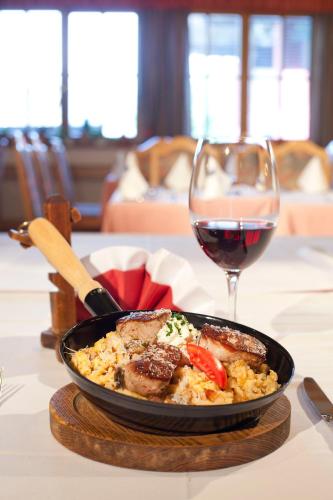 a plate of food with meat and a glass of wine at Hotel Flatscher in Stuhlfelden