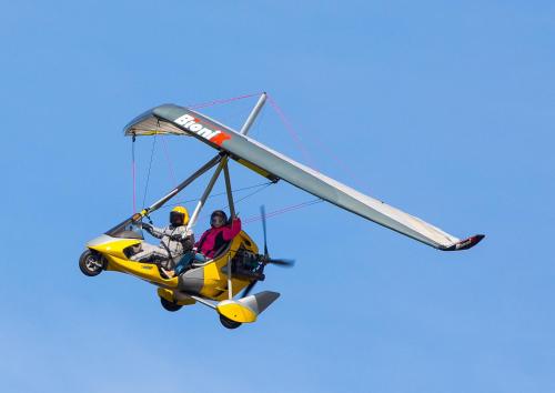 two people in a yellow plane flying in the sky at Forest Edge Lodge in Rīga