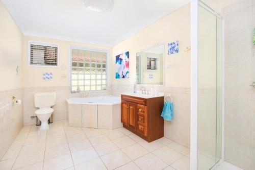 uma casa de banho com uma banheira, um lavatório e um WC. em Michael Street 39 Golden Beach em Caloundra