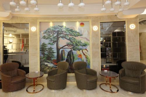 a lobby with chairs and tables in front of a painting at Parliament Palace Hotel in Khujand