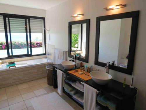 a bathroom with two sinks and a tub and two mirrors at Villa 'Florence' avec longue piscine et vue mer panoramique in Saint-Gilles les Bains