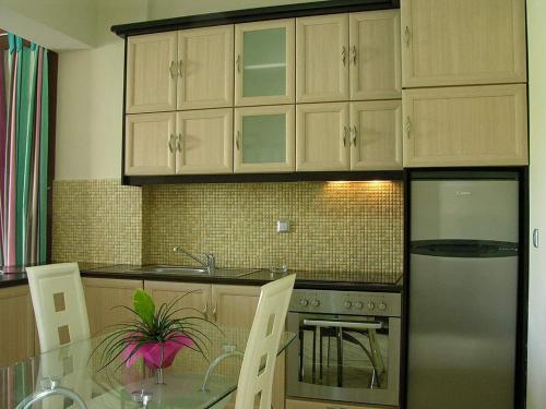 a kitchen with a glass table and a refrigerator at Antonios Village Hotel & Apartments in Arkoudi