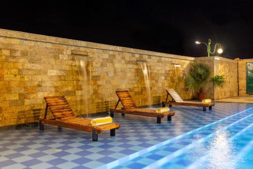 three chairs sitting next to a swimming pool at night at Sairafort Sarovar Portico in Jaisalmer