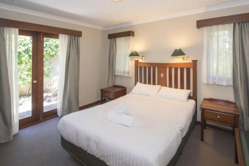 a bedroom with a large white bed and windows at Margaret River Resort in Margaret River Town