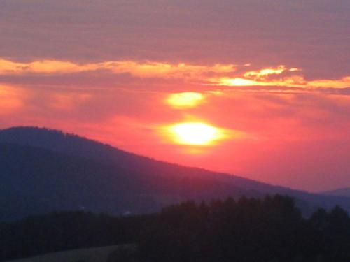 a sunset with the sun setting over a mountain at Wellness Ferienwohnungen Zellertalblick in Drachselsried