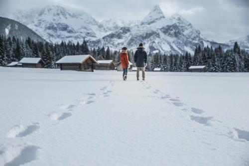 a couple walking through the snow with mountains in the background at Mellow Mountain Hostel in Ehrwald