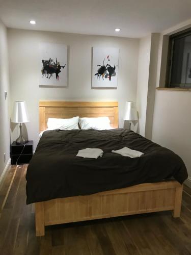a bedroom with a large black bed with two lamps at Hakuba West Coast Inn, Villa in Hakuba
