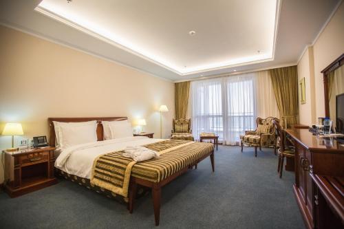 a hotel room with a large bed and a desk at Caspian Riviera Grand Palace Hotel in Aktau