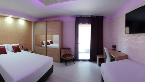 um quarto de hotel com duas camas e uma televisão em L'Hôtel du Lac Casteljaloux em Casteljaloux