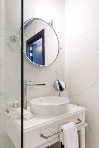 a white bathroom with a sink and a mirror at Hotel Cocoon in Ostend