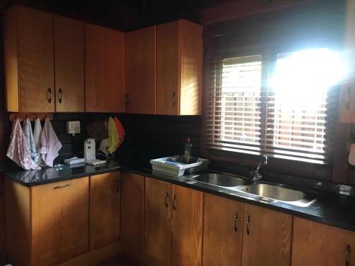 a kitchen with wooden cabinets and a sink and a window at Sodwana Bay Lodge House 34 in Sodwana Bay