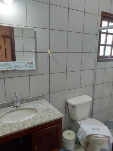 ein Badezimmer mit einem WC, einem Waschbecken und einem Spiegel in der Unterkunft Pousada Maui in Ubatuba