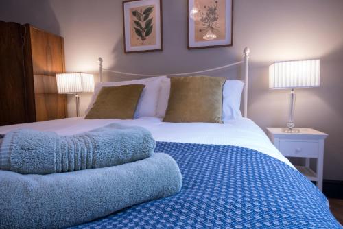 1 dormitorio con 1 cama con manta azul y 2 lámparas en The Little St Apartment, en Macclesfield