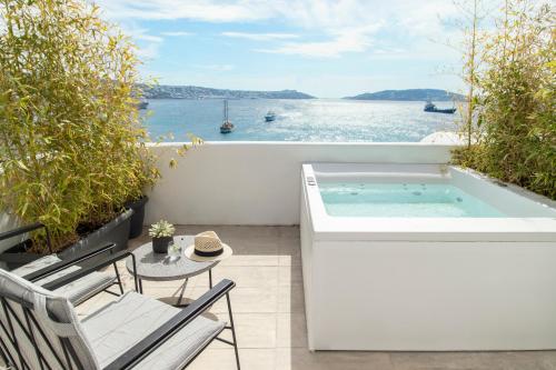 bañera de hidromasaje en el balcón con vistas al agua en Nimbus Mykonos, en Agios Stefanos
