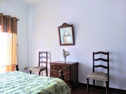 a bedroom with a bed and two chairs and a mirror at Casa Vale do Rio Ovil in Baião