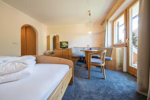 a bedroom with a bed and a table with a chair at Hotel Weingarten in Appiano sulla Strada del Vino