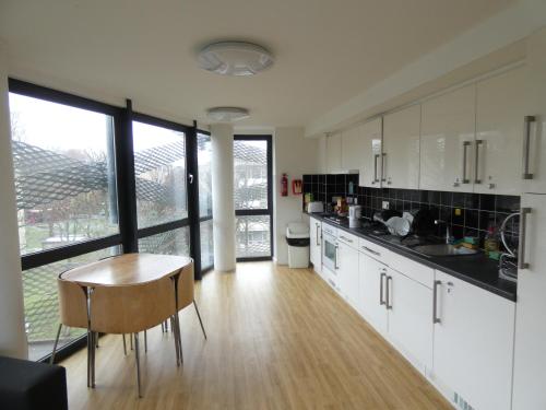 a kitchen with white cabinets and a table and chairs at Newington Court (Stoke Newington) in London