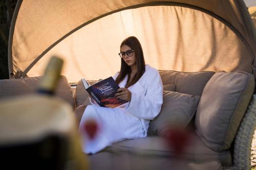 a woman sitting on a couch reading a book at Hotel Weingarten in Appiano sulla Strada del Vino