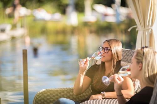two women sitting in a chair drinking wine at Hotel Weingarten in Appiano sulla Strada del Vino