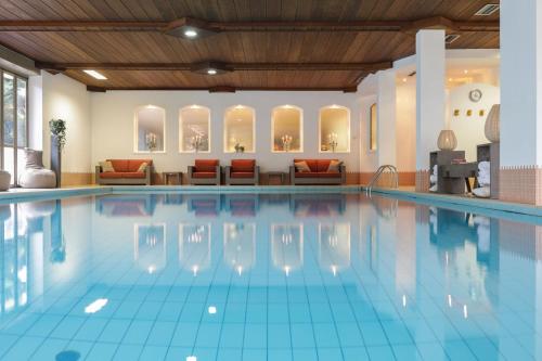 a swimming pool in a hotel with couches at Hotel Weingarten in Appiano sulla Strada del Vino
