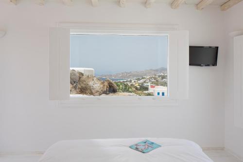 a bedroom with a window with a bed and a tv at Aether Boutique Stay in Glastros