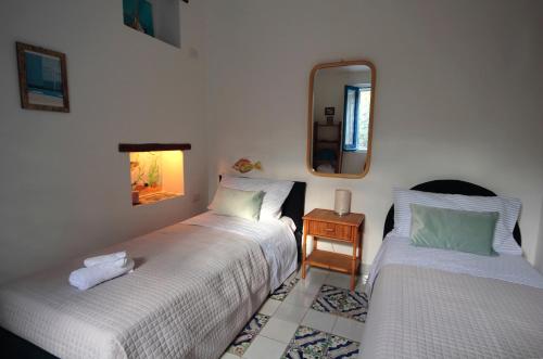 2 camas sentadas en una habitación con espejo en Villa delle terrazze, en Punta Secca