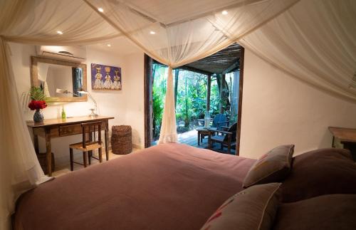 a bedroom with a large bed and a desk and a window at Casa Angatu in Trancoso