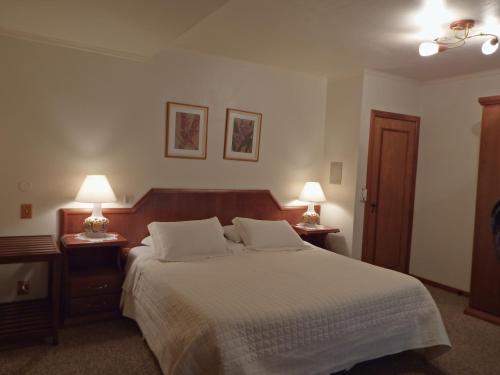 a bedroom with a large bed with two night stands and two lamps at Hotel Azaleia in Gramado