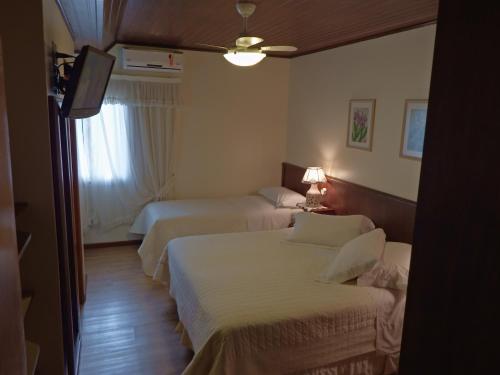 a hotel room with two beds and a window at Hotel Azaleia in Gramado