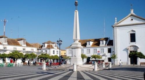 a white building with a monument in the middle of a street at Apartamento Central in Vila Real de Santo António