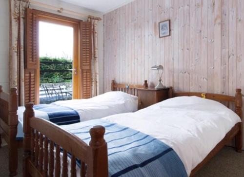 Seaside Cottage في ويكسفورد: سريرين في غرفة نوم مع نافذة