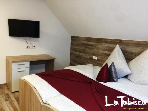 um quarto com uma cama e uma televisão na parede em Hotel Schurwald em Rechberghausen