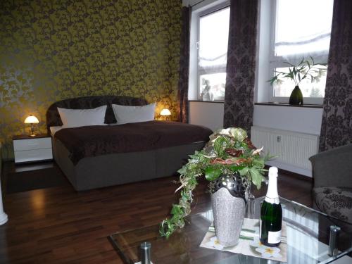 a bedroom with a bed and a table with a bottle of wine at Hotel am Schützenberg in Gotha