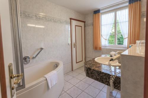 bagno con vasca e lavandino di Villa Katharina Ferienwohnungen a Willingen