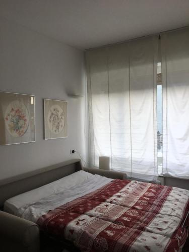 Schlafzimmer mit einem Bett und einem Fenster mit Vorhängen in der Unterkunft Casa Sinigaglia in Como