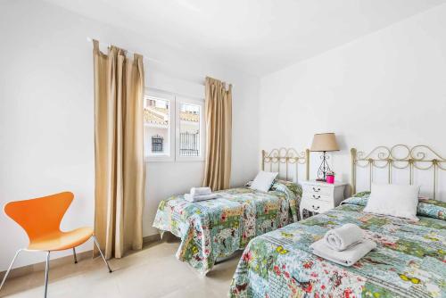 a bedroom with two beds and a chair in it at Villa Valeria in Nerja