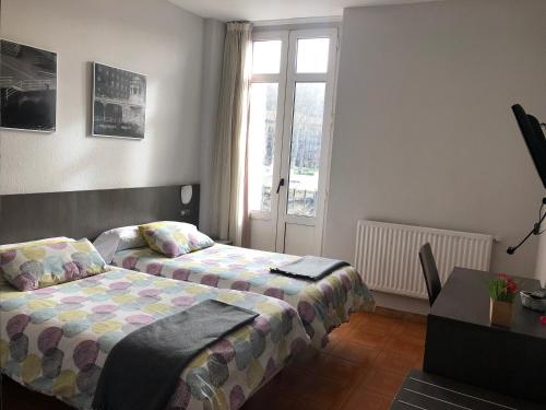 a bedroom with two beds and a table and a window at Hotel Ripa in Bilbao