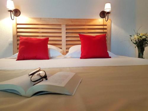 un livre et une paire de lunettes sur un lit dans l'établissement Résidence Goélia Le Domaine des Glénan, à Fouesnant
