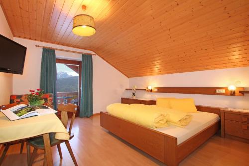 a bedroom with a bed and a table and a window at Schmözlhof in Tesido