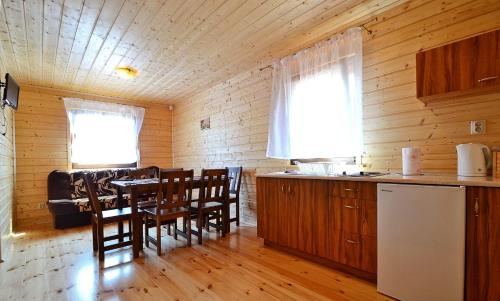a kitchen and dining room with a table and chairs at Domki u Małgosi in Rusinowo