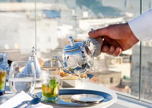 a man is holding a tea pot on a table at Riad Dar Saba - Saba's House in Tangier
