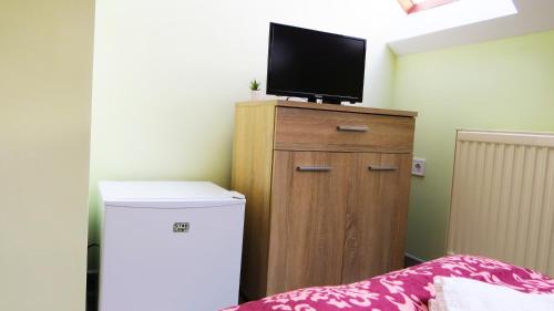 a room with a refrigerator and a tv on a cabinet at Hőforrás Wellness Vendégház in Egerszalók