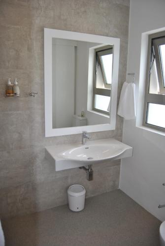 a bathroom with a white sink and a mirror at Oceans Guest House & Luxurious Apartments in Struisbaai