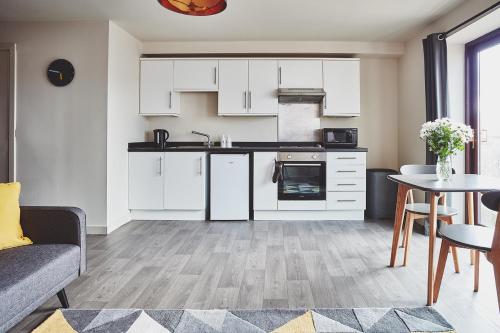 cocina y sala de estar con armarios blancos y mesa en The Ranald Apartments, en Oban