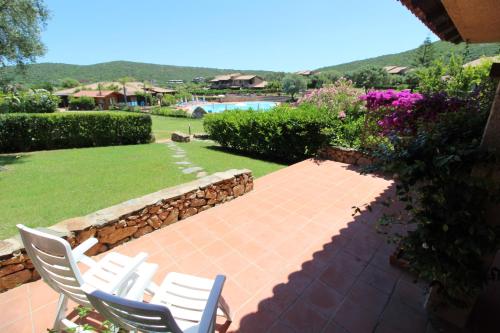 ein Paar Stühle auf einer Terrasse mit Garten in der Unterkunft Appartamenti residence Vela Blu Golfo Aranci in Marinella