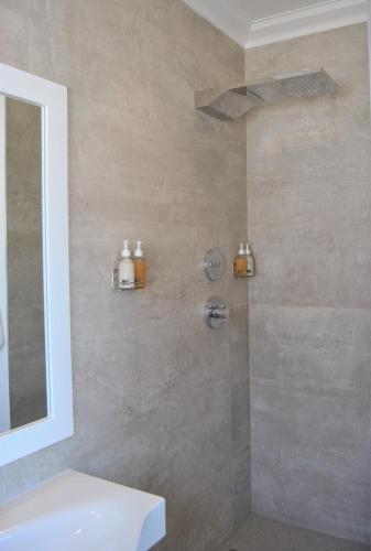 a bathroom with a shower with a sink and a mirror at Oceans Guest House & Luxurious Apartments in Struisbaai